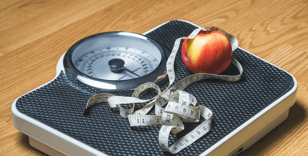 Weegschaal met meetlint en appel erop