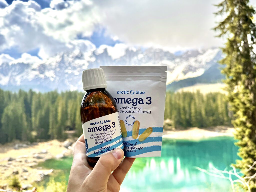 Arctic blue visolie vloeibaar en tabletten met een meer en een bos op de achtergrond